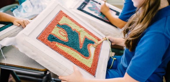 Photo of school student working on punch needle rug project